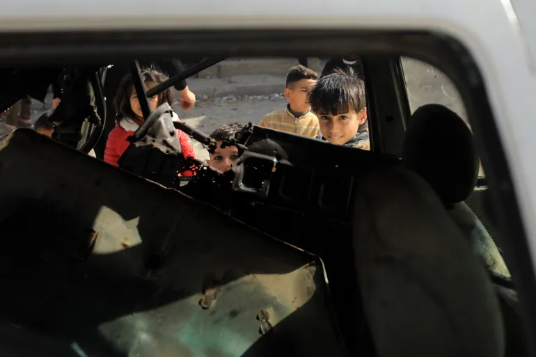 Enfants à Rafah contemplant une voiture détruite par une frappe israélienne le samedi.
