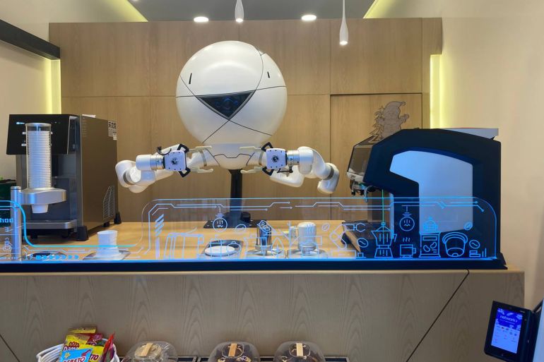 Le robot prépare un café au milieu des voitures anciennes exposées