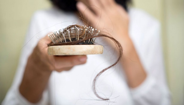 Femme examinant ses cheveux, inquiète de la perte de densité capillaire liée au stress.