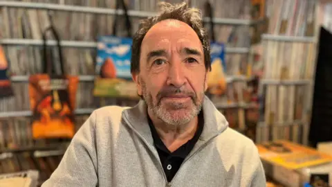 Rab Smith, propriétaire d'un magasin de disques, devant ses vinyles