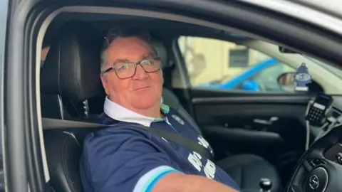 Stuart Brack, chauffeur de taxi, au volant de son véhicule