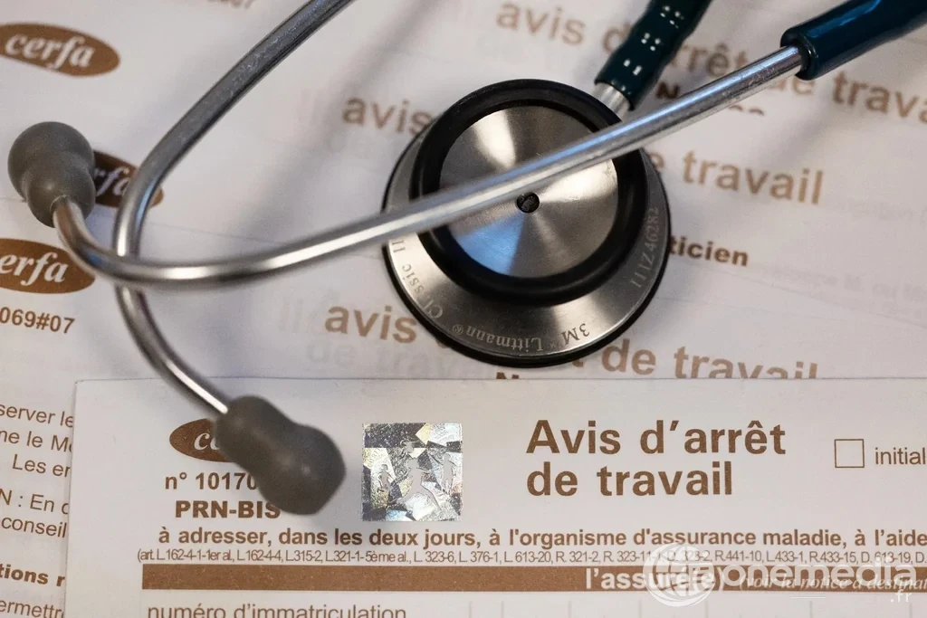 Pile de formulaires d'avis d'arrêt de travail posée sur un bureau, à côté d'un cachet de médecin — illustration du décret du 13 juin 2026