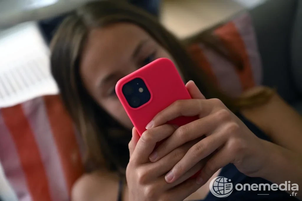 Adolescente consultant un smartphone, illustration de l'accès des mineurs aux réseaux sociaux