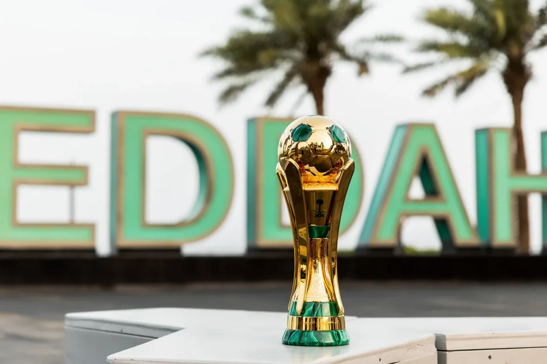 Le trophée doré de la Coupe du Roi d’Arabie saoudite posé devant des palmiers.
