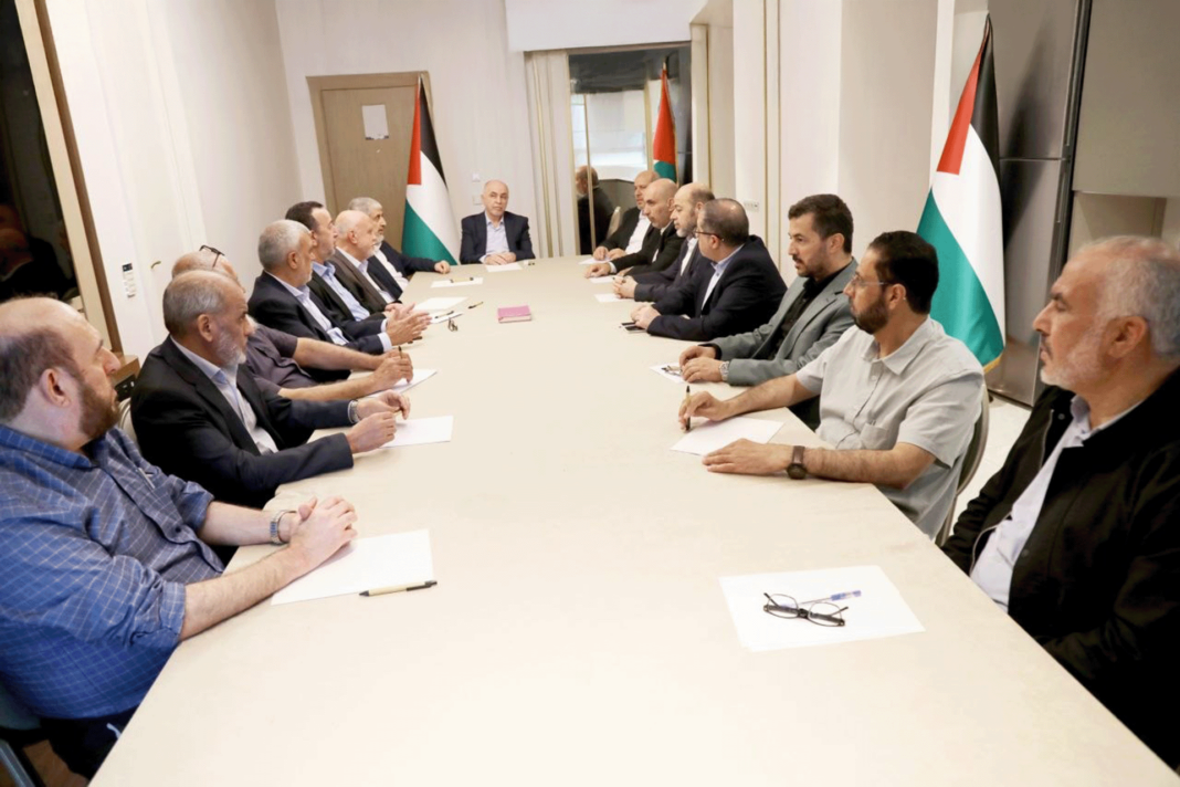 Des responsables du Hamas réunis autour d’une table, devant des drapeaux palestiniens.