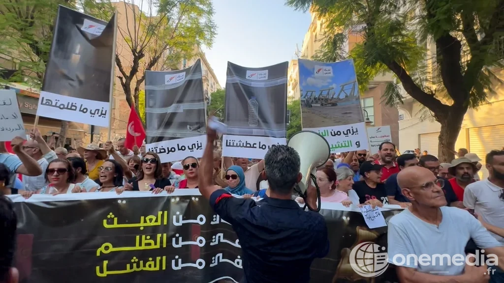 Des manifestants défilent à Tunis avec des pancartes et un drapeau tunisien.